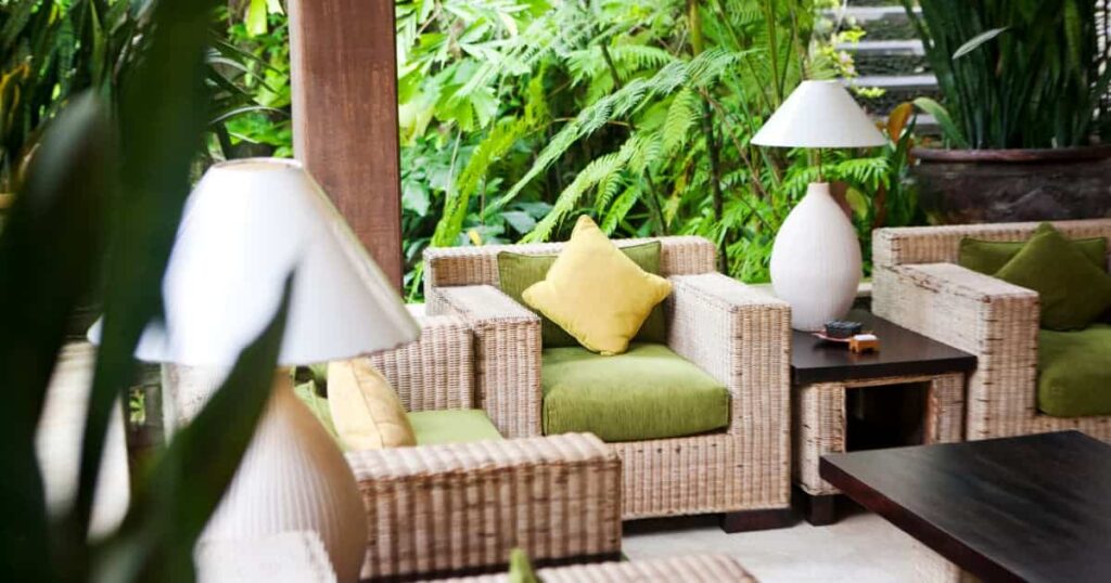 veranda décorée avec lampes et fauteuils et autour pleins de plantes comme des fougères